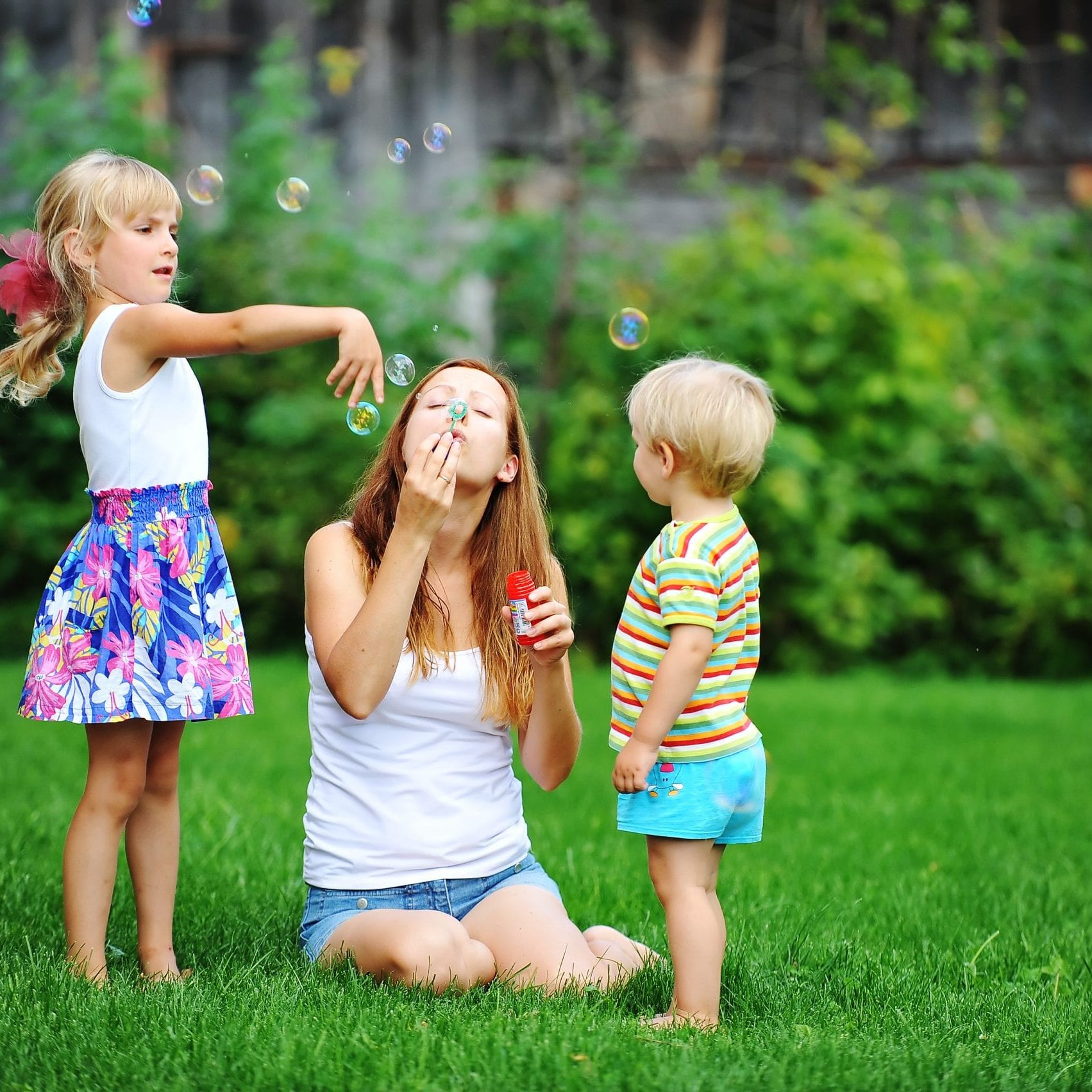 Mother,And,Her,Children,Play,With,Bubble,Blower,On,Green